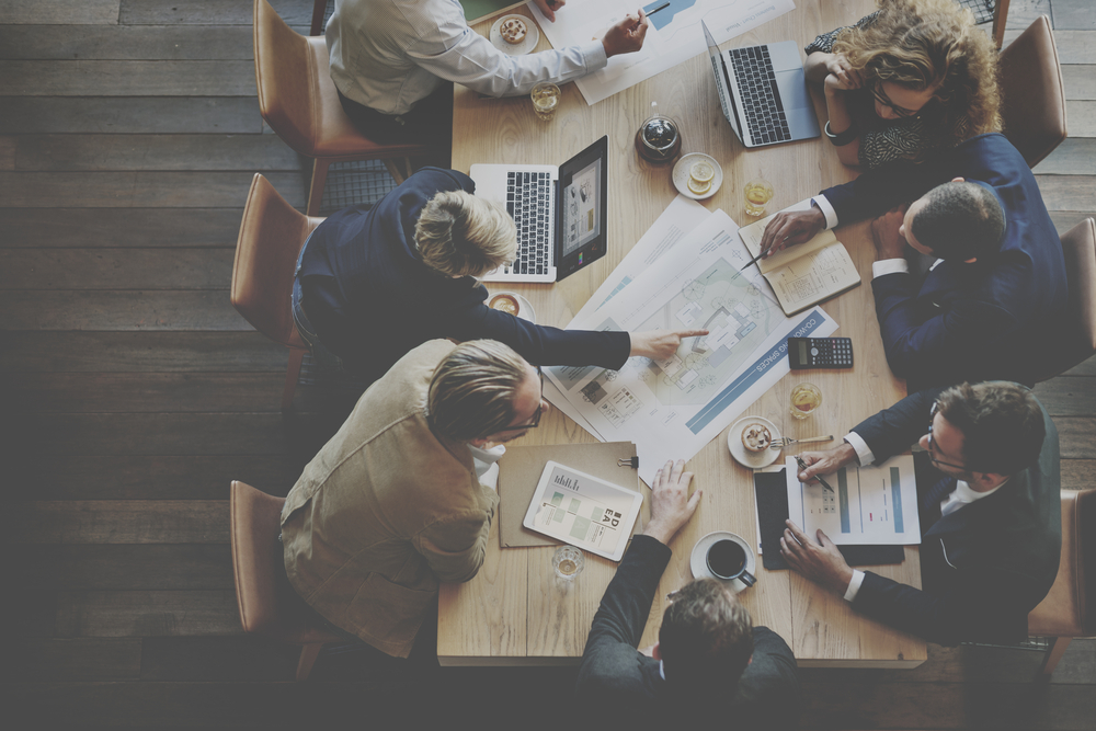 A team of professionals sitting together at a table, each with a laptop, working on a project.