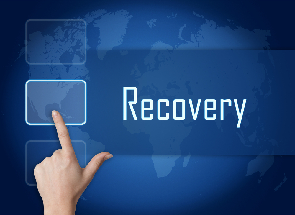 Hand pressing a recovery button against a blue background, symbolizing a reset or recovery action.