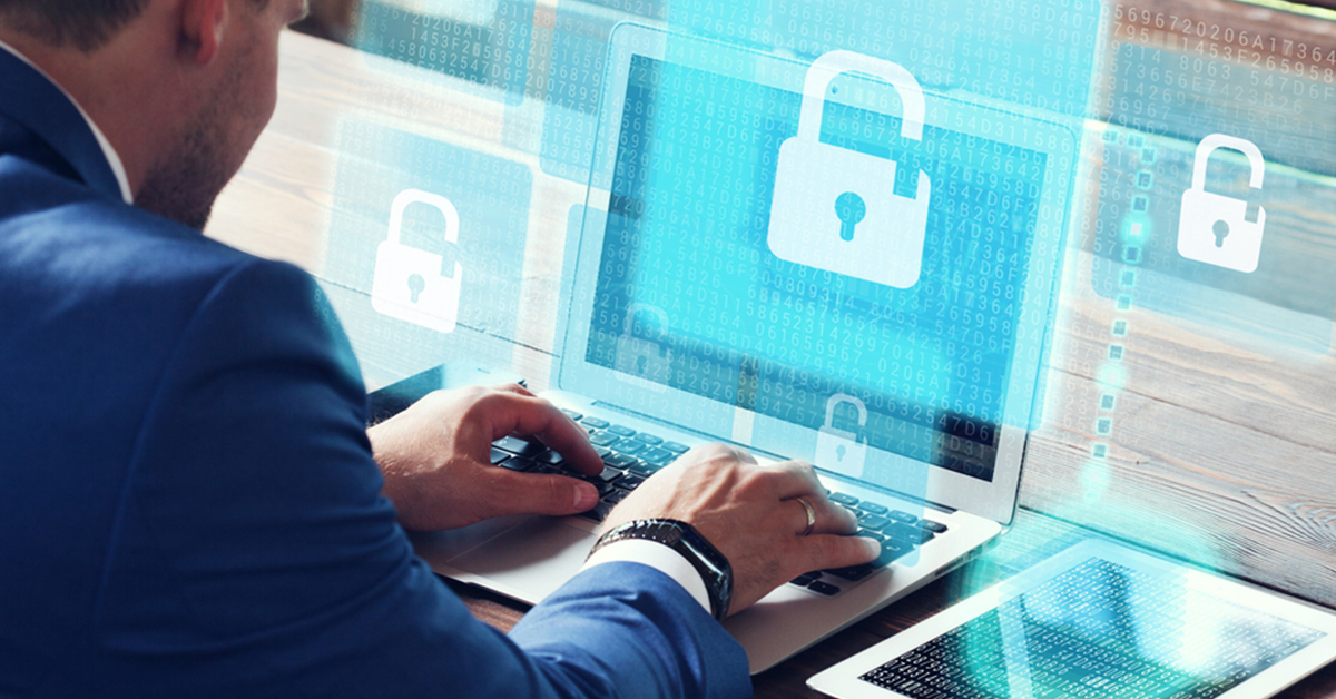 A man in a suit works on a laptop displaying a padlock icon, indicating a focus on security and data protection.