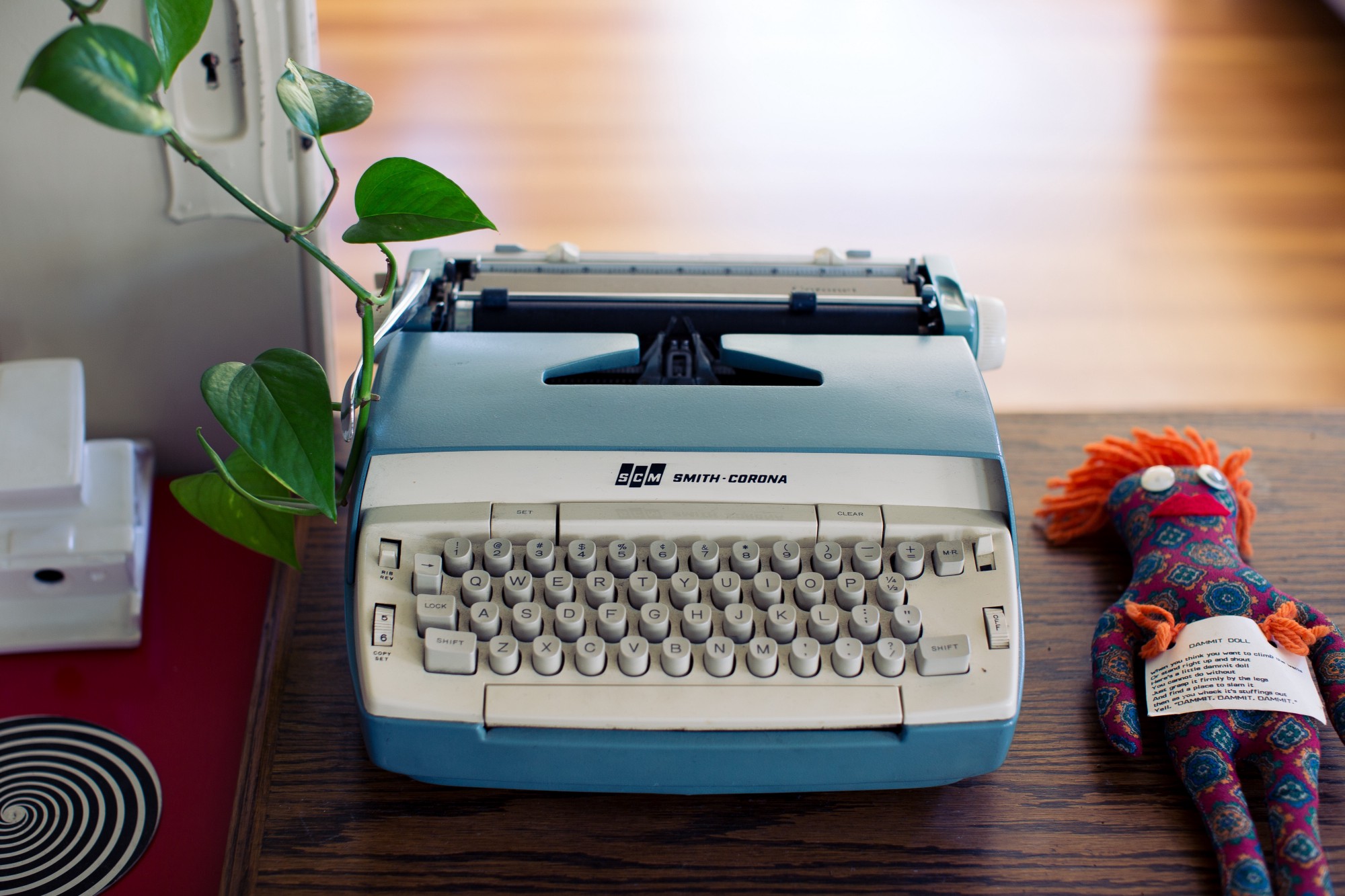 A vintage typewriter and a plush stuffed animal sit on a wooden table, creating a nostalgic and cozy atmosphere.