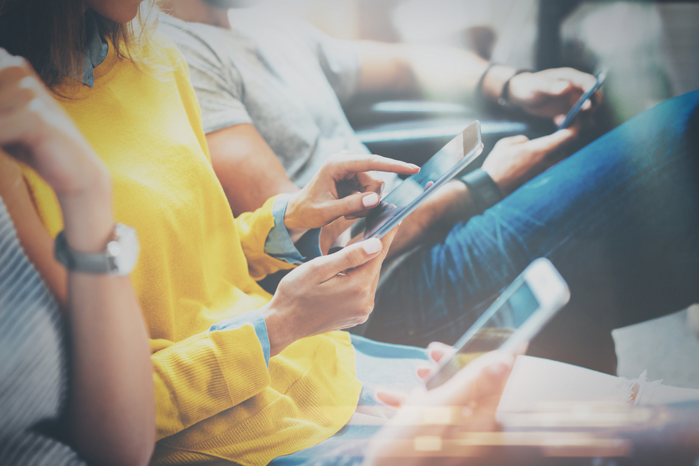 Several individuals sitting and engaged with their mobile phones.