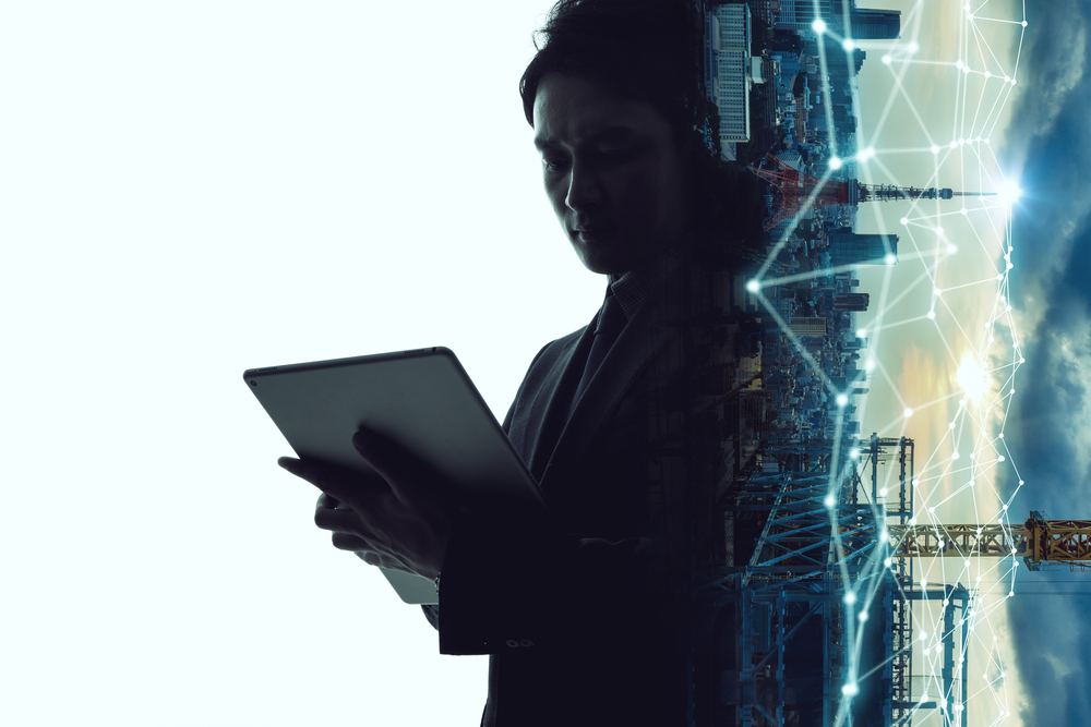 A man in a suit holding a tablet computer, looking engaged and focused on the device.