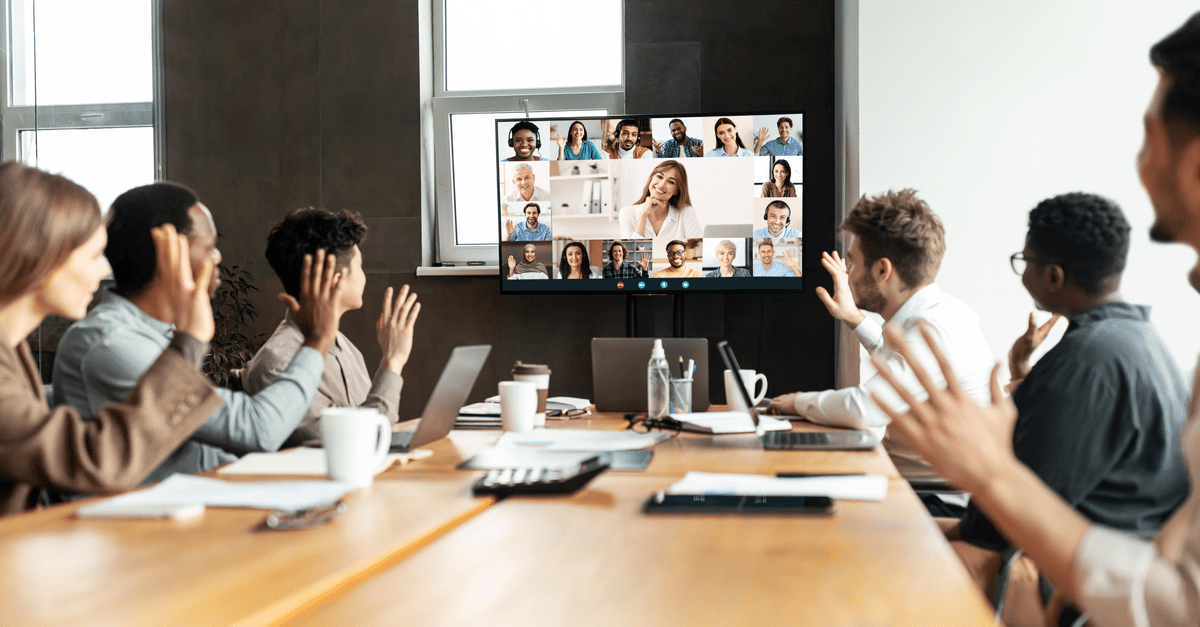 Attendees in a conference room with hands up, actively participating in an online conference.