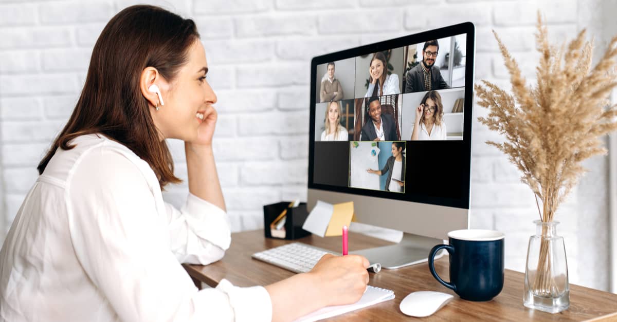 A woman at her desk, engaged in a video conference on her computer screen.