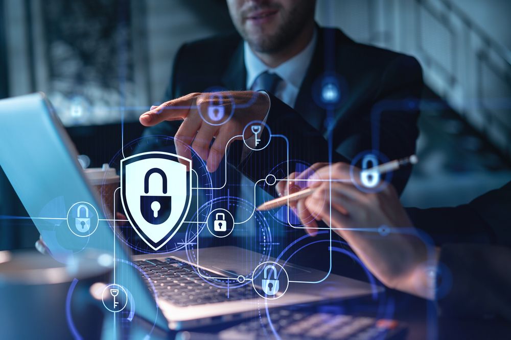 Team of business individuals working on a laptop, highlighted by a padlock icon representing cybersecurity measures.