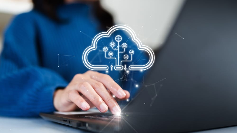 Woman working on a laptop displaying a cloud icon on the screen, indicating cloud computing or storage.