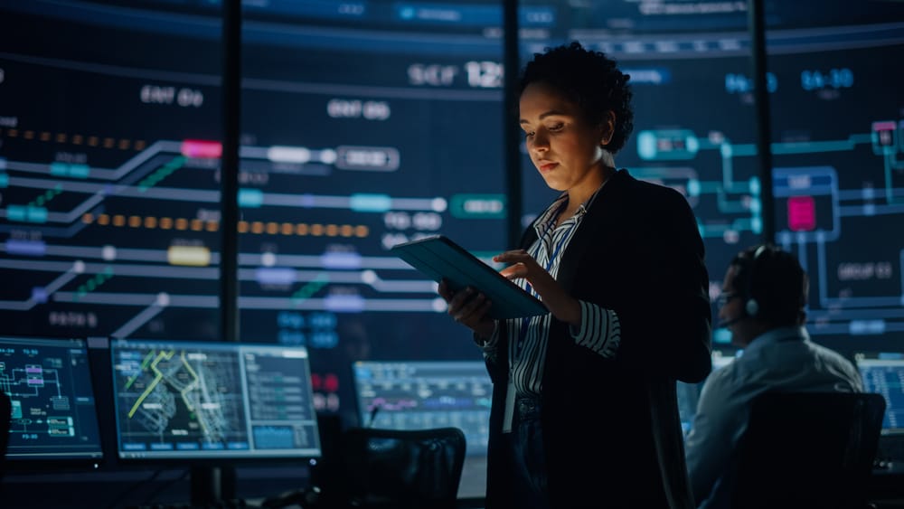 A woman in a business suit intently examines a tablet computer in a professional setting.